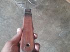 একটা মোটা কাঠের হ্যান্ডেল ওয়ালা ছাকনি।